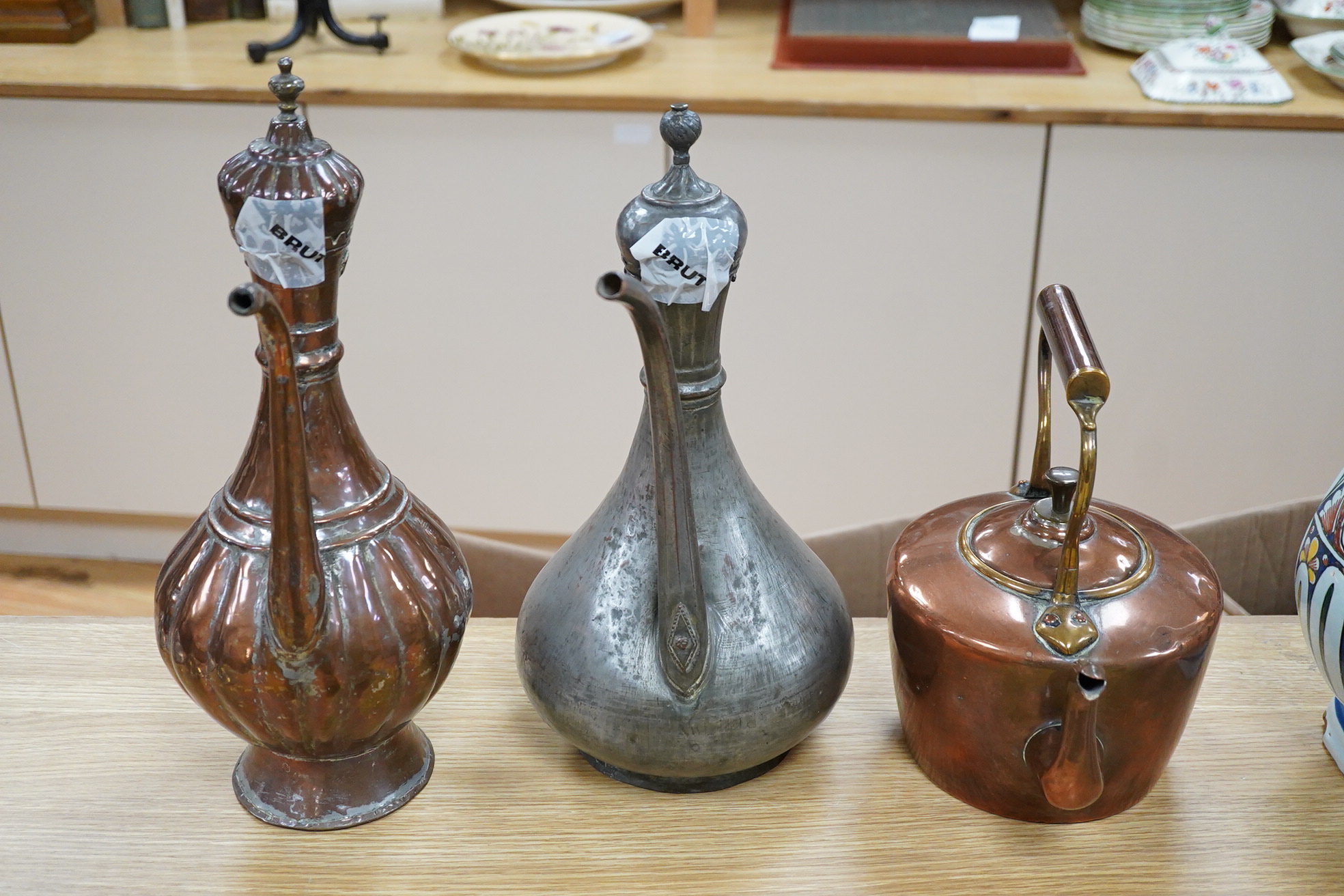 Two Middle eastern tinned copper coffee pots ‘Dallah’ a similar dish and a European copper kettle, tallest 41cm high